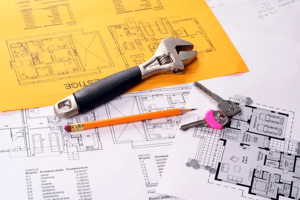 Tools on house plans including pencil, keys and monkey wrench.