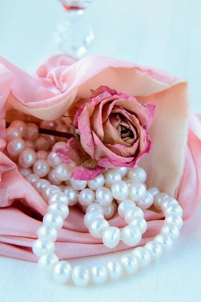 White pearls in a pink bag with a rose