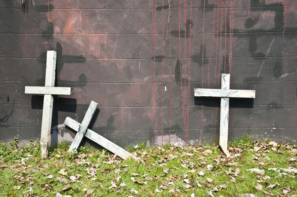 Three wooden crosses lean on the wall