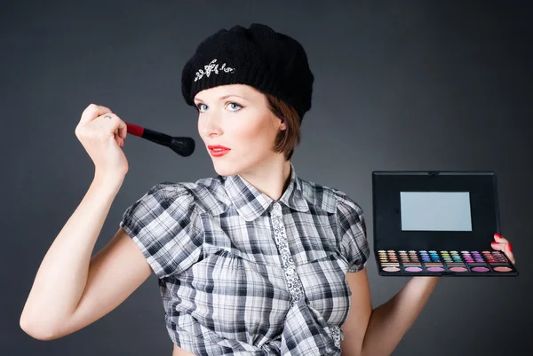 Young woman with makeup palette and brushes