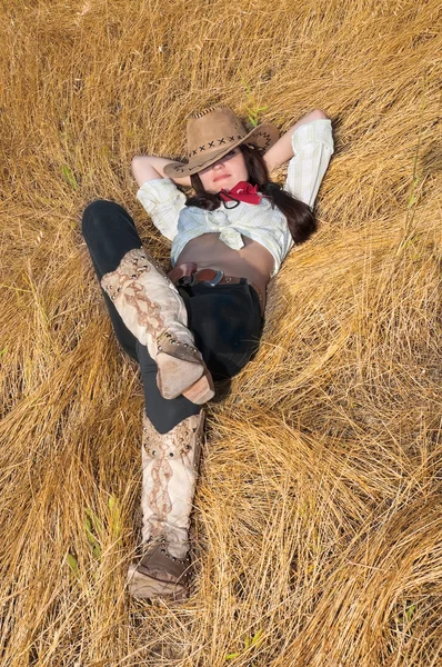 Cowboy girl lying in a field of grass