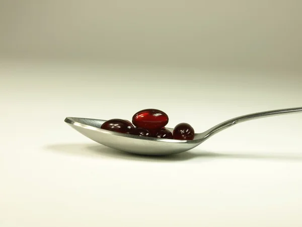 Red capsules on a spoon