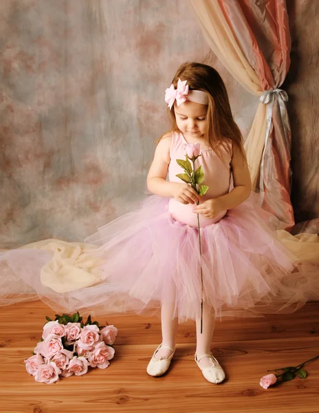 Little ballerina beauty holding a pink rose