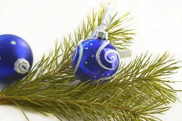 Blue balls on a white background and branch of pine