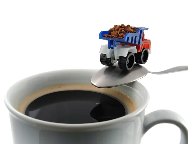 Coffee cup and spoon with toy truck ready to load coffee grain