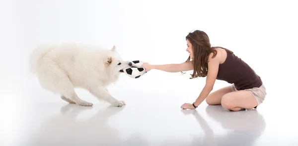 Young woman and dog playing with a ball