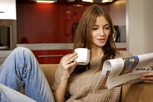 Mid adult woman drinking coffee and reading news