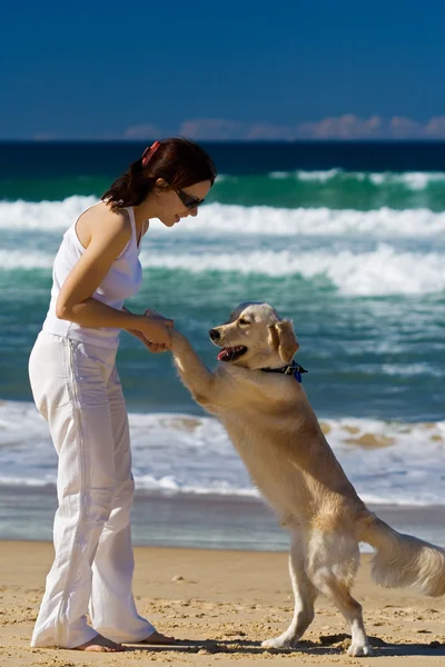 Young female dancing on a beach with a dog