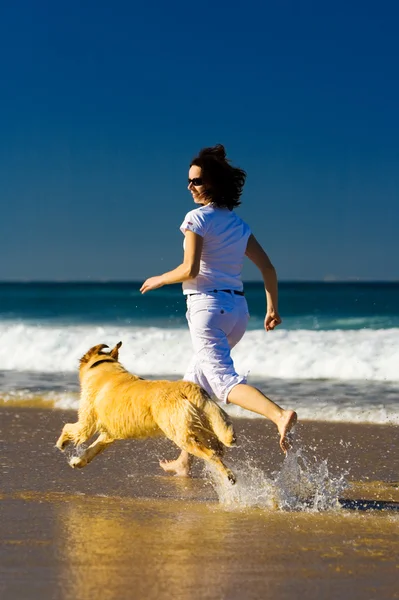 Young woman and dog running on the beach