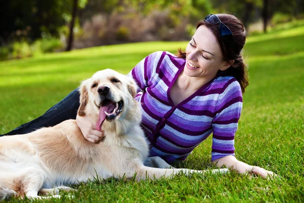 Young woman and golden retriever in the grass