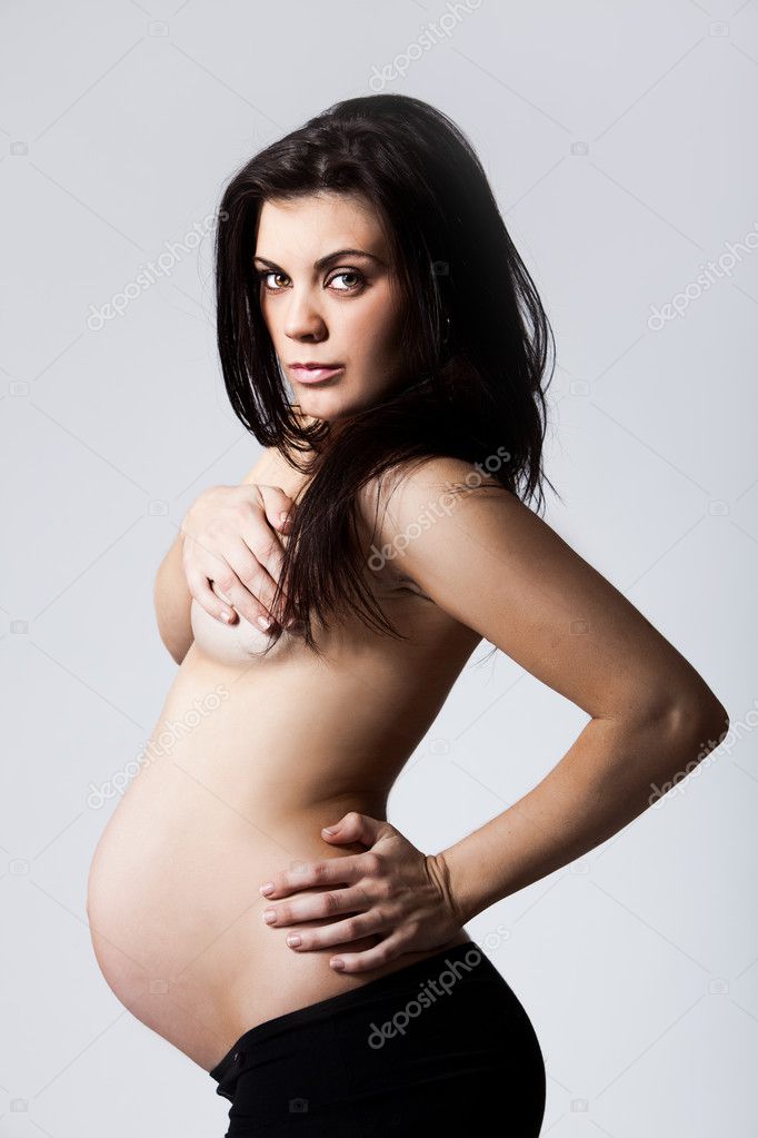 Young pregnant woman from side covering her breasts