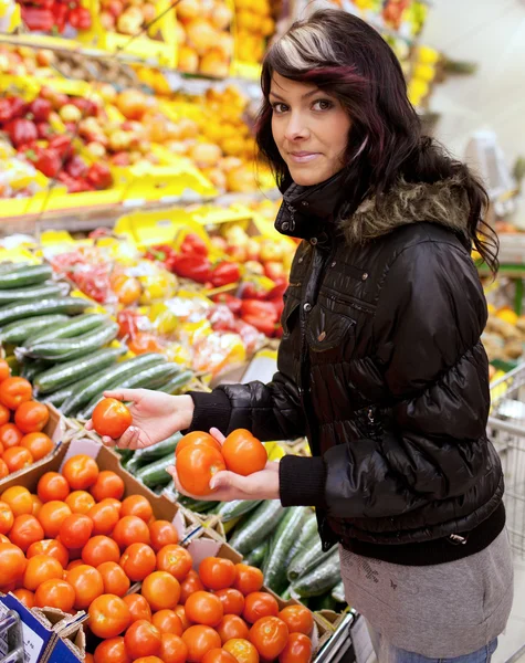 Beautiful young woman buying fruits and vegetables at a produce