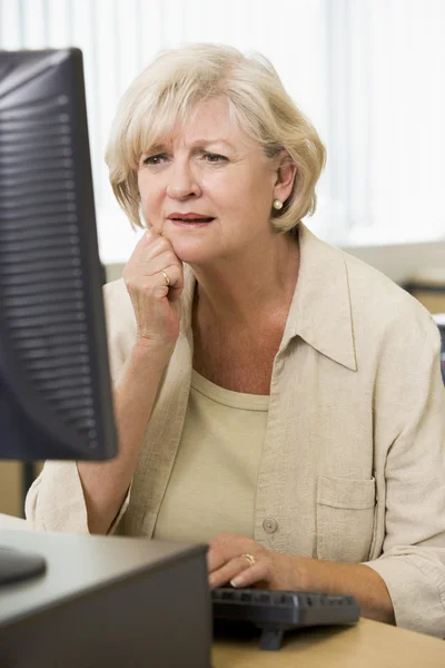 Confused woman frowning at computer monitor