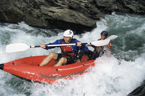 Two paddling inflatable boat down rapids