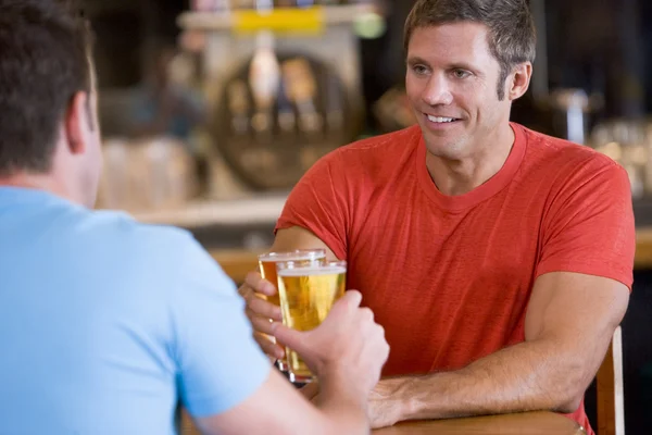 Two men toasting beer in a bar