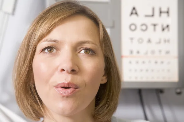 Woman in optometrist's exam room taking deep breath