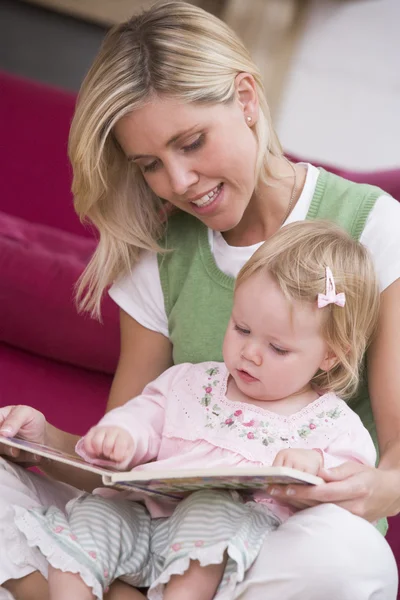 Mother in living room reading book with baby smiling