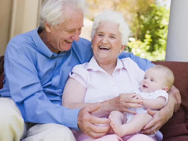 Grandparents outdoors on patio with baby smiling