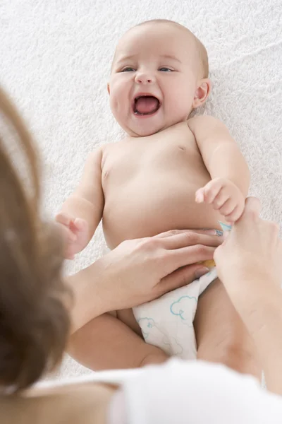 Mother changing baby\'s diaper indoors