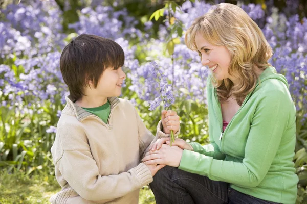 Mother and son outdoors holding flowers smiling