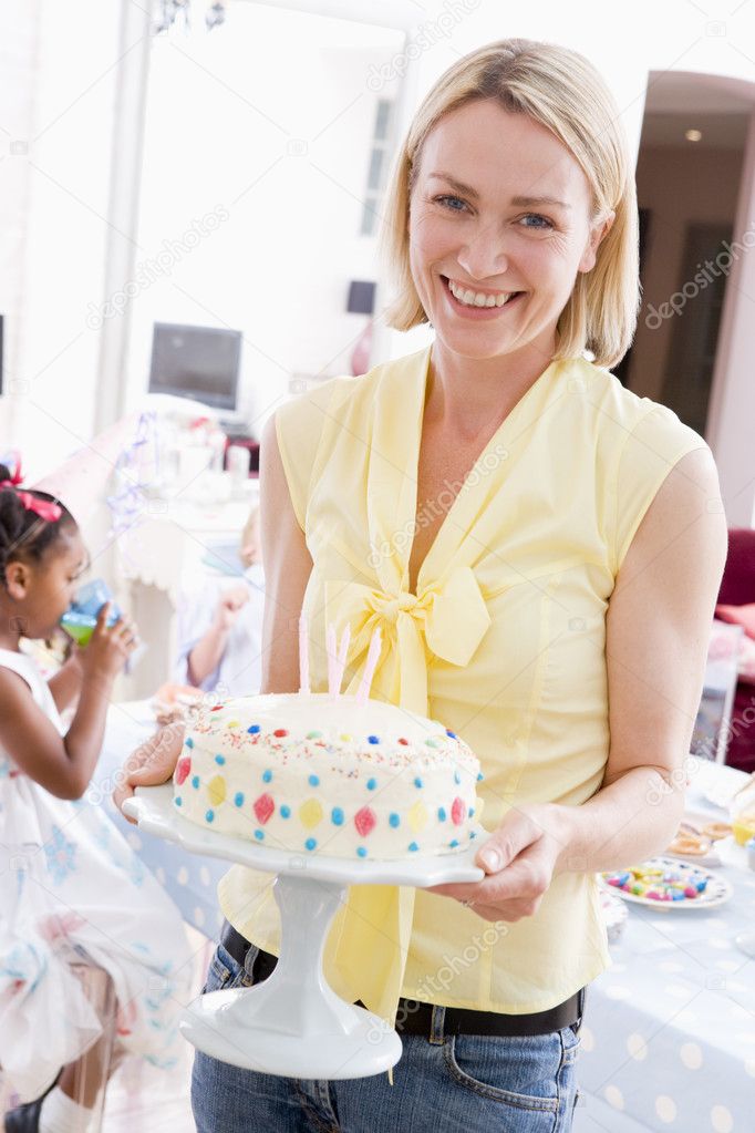 Woman at party holding birthday cake smiling — Stock Photo