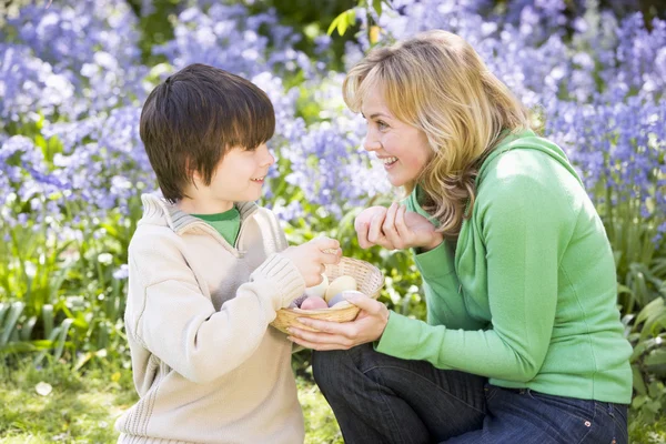 Mother and son on Easter looking for eggs outdoors smiling
