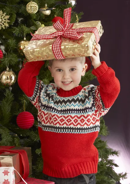 Young Boy Holding Christmas Present In Front Of Christmas — Stock Photo #4841002