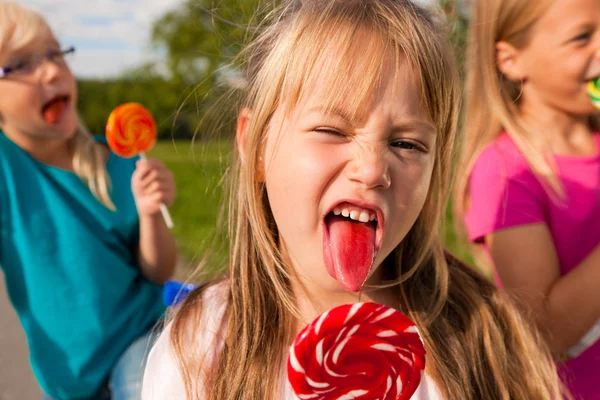Three girls eating lollipops, the