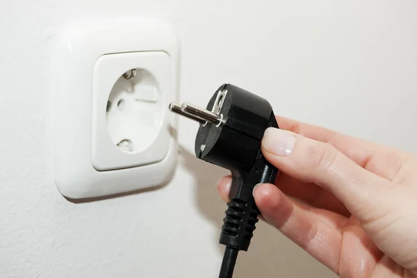 Female hand unplugging a plug