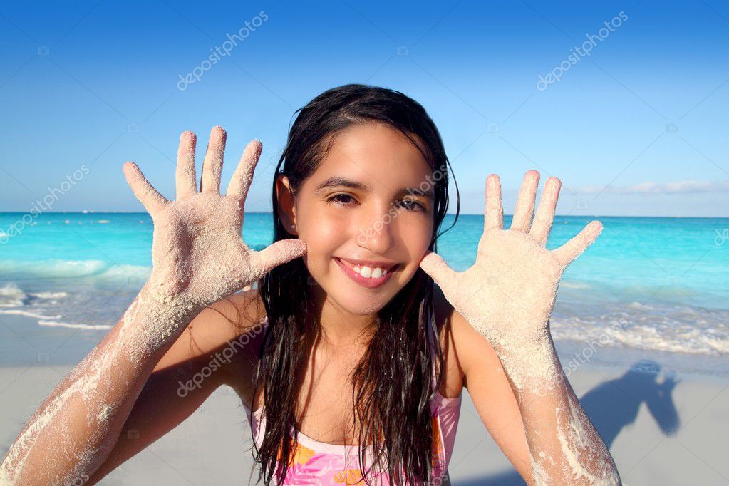 Latin indian teen girl playing beach showing sandy hands in Caribbean 