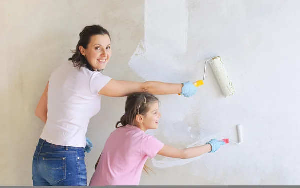 Happy Mother and douther painting a wall with roller