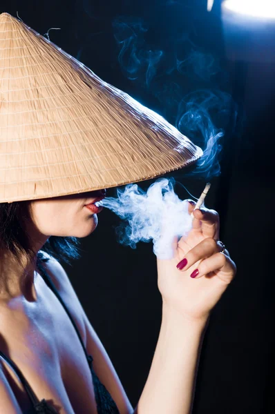 stock image Woman in the Vietnamese hat smoking a cigarette