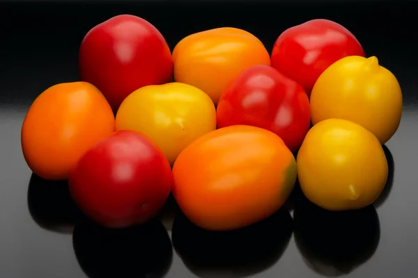 Multicolored tomatoes on a black backgrouns — Stock Photo, Image