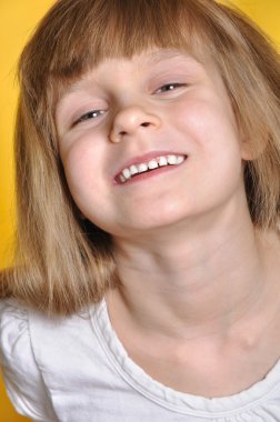 Naughty smiling little girl . Yellow background. clipart