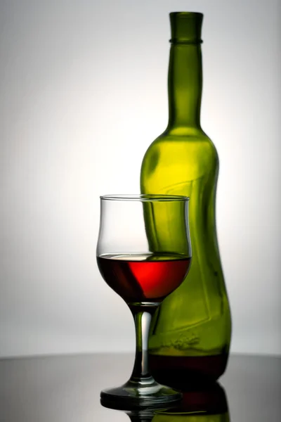 Винное стекло и бутылка на столе . — стоковое фото