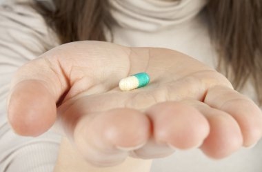 Woman holds a pill in a hand clipart