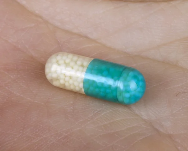 Uma pílula nos backgrouds mão — Fotografia de Stock