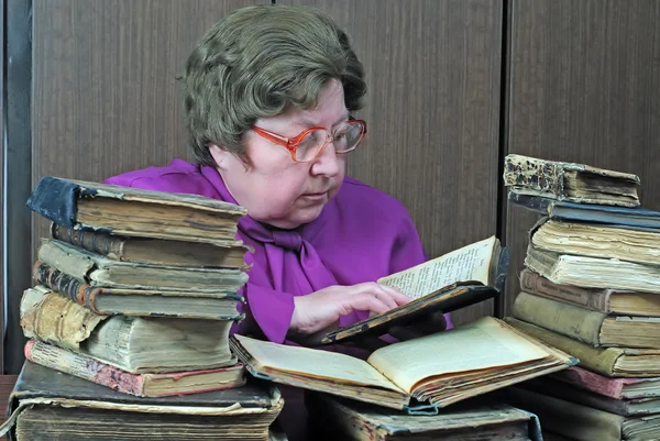 stock image Old woman in library with religious books