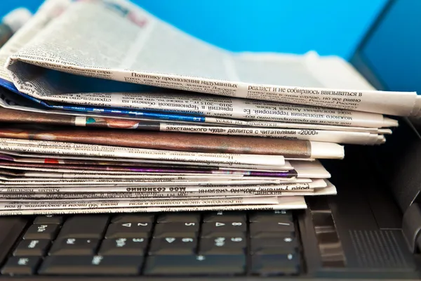 Pilha de jornais no computador portátil — Fotografia de Stock