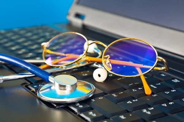 Estetoscópio e óculos no laptop preto — Fotografia de Stock
