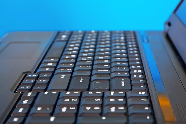 Schwarzer Laptop auf blauem Hintergrund — Stockfoto