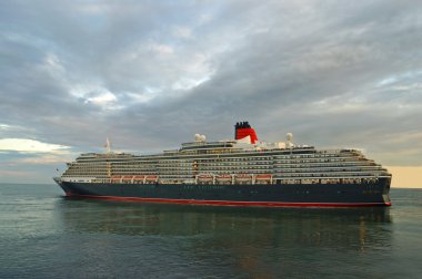 Cruise ship in a sea against a dramatic sunset sky clipart