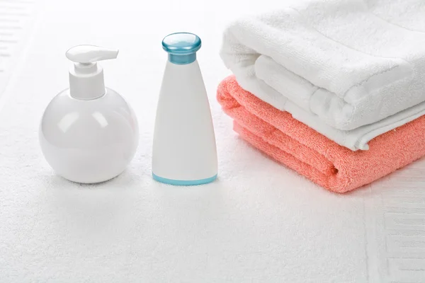 Bottiglie con asciugamani di cotone su sfondo bianco — Foto Stock