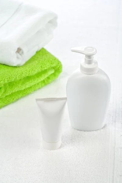 Bottle tube and towels on white background — Stock Photo, Image
