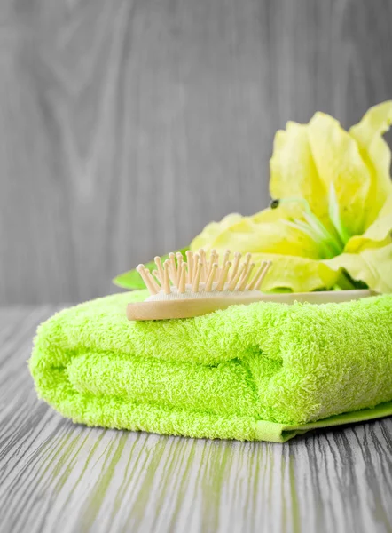 Gele bloem op groene handdoek met haarborstel — Stockfoto