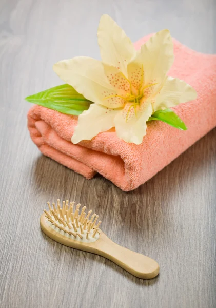 Bloem op roze handdoek met haarborstel — Stockfoto