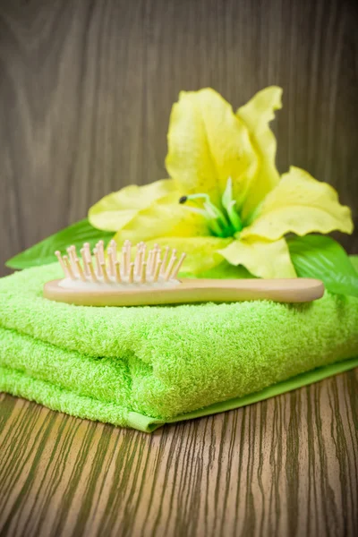 Žlutý květ na ručník a dřevěný kartáč na vlasy — Stock fotografie