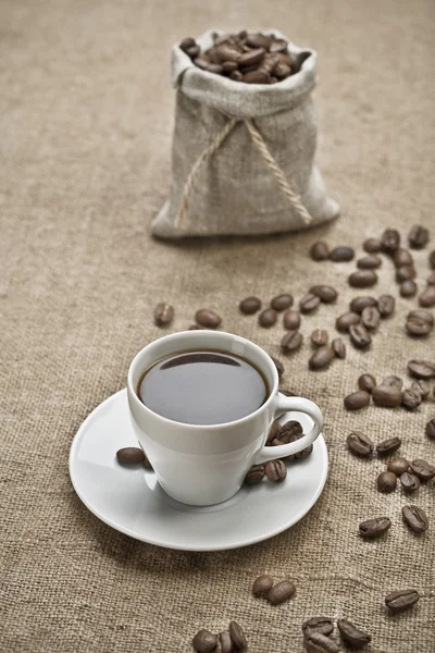 Kaffe korn och kopp kaffe på säckväv — Stockfoto