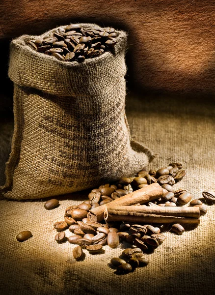 Dark composition of coffee beans and burlap bag — Stock Photo, Image