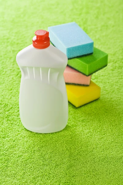 Garrafa e esponjas na toalha verde — Fotografia de Stock